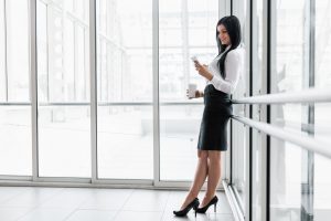 Successful business woman with coffee and smartphone in an office setting
