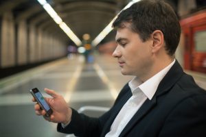Young man reading sms on smartphone in underground